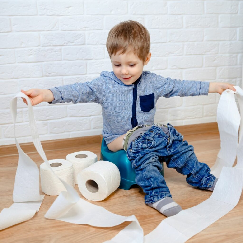 child on potty with toilet paper strewn about